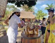  ?? ?? A cenote swimmer, above, tastes a liqueur offered to visitors on the cenote grounds. This Mayan hut, at left, is typical of oneroom dwellings with thatched roofs and without electricit­y.