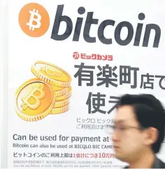  ??  ?? A man walks past a signboard informing customers that Bitcoin can be used for payment at a store in Tokyo. — AFP photo