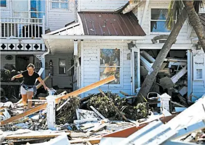  ?? DAVID GOLDMAN/AP ?? Brandy Jessen climbs over debris while retrieving some of her parents’ belongings Friday in Mexico Beach.