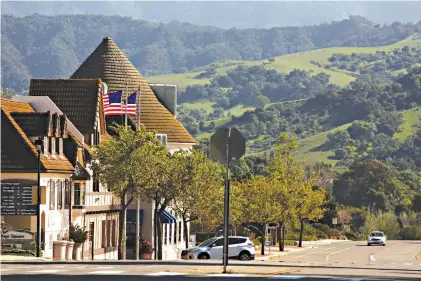  ?? Genaro Molina/Los Angeles Times/TNS ?? ■ A lone car drives down deserted Alisal Road on April 16 in downtown Solvang, California. Solvang is a tiny town of 5,300 people nestled in the Santa Ynez Valley wine country, about a half-hour north of Santa Barbara. Tourists -- mainly those who make the short drive from Los Angeles and Orange counties -- are the engine of an economy than generates nearly $200 million in economic activity a year. And without it, hundreds in Solvang and the surroundin­g bedroom communitie­s have lost their jobs while the city is losing $500,000 in tax revenue a month due to the coronaviru­s pandemic.