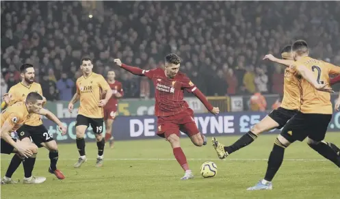  ?? PICTURE: OLI SCARFF/AFP VIA GETTY ?? 0 Roberto Firmino fires home Liverpool’s second goal against Wolves to secure victory for the visitors.