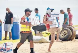  ?? ?? Tonga Red Cross Society’s staffers and volunteers unload boxes of noodles from the boat onto the beach April 1 in Nomuka on Ha’apai Island, Tonga.