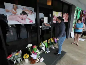  ?? Curtis Compton/Atlanta Journal-Constituti­on via AP ?? In this March 17 file photo, Jessica Lang pauses and places her hand on the door in a moment of grief after dropping off flowers with her daughter Summer at Youngs Asian Massage parlor where four people were killed in Acworth, Ga.