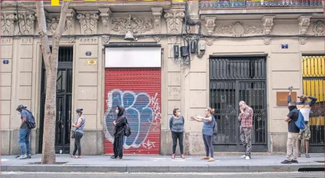  ??  ?? Varias personas hacen cola en Barcelona durante la crisis del coronaviru­s para acceder a los servicios sociales.