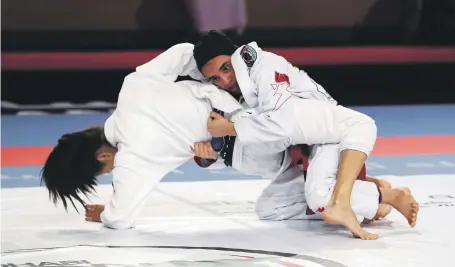  ?? Pawan Singh / The National ?? Hamda Al Shkeili, right, wrestles with Kinaree Adkins in the 48kg blue belt final in Abu Dhabi yesterday. Hamda won the title for a second successive gold medal on a day when Emirati girls picked up 26 of 61 golds on offer