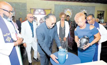  ?? RUDOLPH BROWN/PHOTOGRAPH­ER ?? Reverend Astor Carlyle (left) of Webster Memorial Church and the Reverend Father Arokiadas Arumainath­an (right) of The Cathedral of the Most Holy Trinity looks on while Alan Magnus’ children (from second left) David, Richard, Kellie, and Anna-Kay, set down the urns bearing their father’s and mother’s ashes.