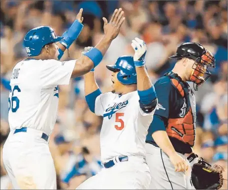  ?? Wally Skalij Los Angeles Times ?? JUAN URIBE celebrates his two-run home run with Yasiel Puig that gave the Dodgers a 10-4 lead over the Braves in the fourth inning.