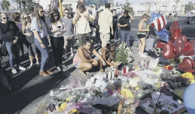  ?? PICTURE: AP ?? People light candles at a makeshift memorial for victims of the mass shooting in Las Vegas in which 58 people were killed and 500 injured