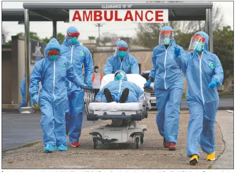  ?? (File Photo/AP/David J. Phillip) ?? A person is taken on a stretcher into the United Memorial Medical Center after going through testing for covid-19 on March 19 in Houston. People were lined up in their cars in a line that stretched over 2 miles to be tested in the drive-through testing for coronaviru­s.