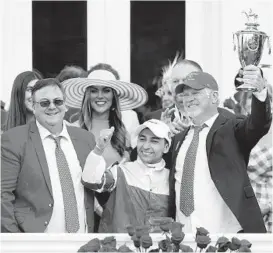  ?? JAMIE SQUIRE/GETTY ?? From left, trainer Eric Reed, jockey Sonny Leon and owner Rick Dawson celebrate with the trophy after Rich Strike won the 148th running of the Kentucky Derby at Churchill Downs on Saturday in Louisville, Ky.