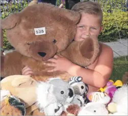  ?? FM3353792 ?? Billy Chapman, six, has a hug for a giant teddy on the tombola stall