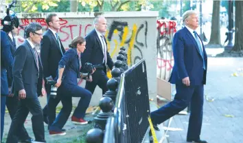  ?? (Tom Brenner/Reuters) ?? US PRESIDENT Donald Trump walks past a building defaced with graffiti by protesters in Lafayette Park, on his way back to the White House after a photo opportunit­y at St John’s Church on Monday.