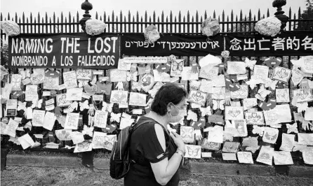  ?? MARK LENNIHAN/AP ?? A woman makes her way past a cemetery fence adorned with tributes to COVID-19 victims last month in New York. The U.S. death toll is about 120,000.