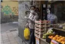  ??  ?? A woman leaves a fruit store in Madrid wearing a protective mask and gloves. Photograph: Pablo Blázquez Domínguez/ Getty Images