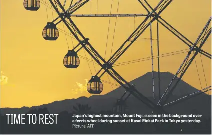  ?? Picture: AFP ?? Japan’s highest mountain, Mount Fuji, is seen in the background over a ferris wheel during sunset at Kasai Rinkai Park in Tokyo yesterday.