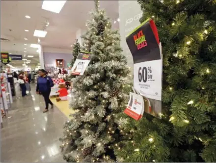  ?? ELAINE THOMPSON — THE ASSOCIATED PRESS ?? A shopper walks past a display of artificial Christmas trees at a JCPenney store Friday in Seattle. Black Friday has morphed from a single day when people got up early to score doorbuster­s into a whole season of deals, so shoppers may feel less need to...