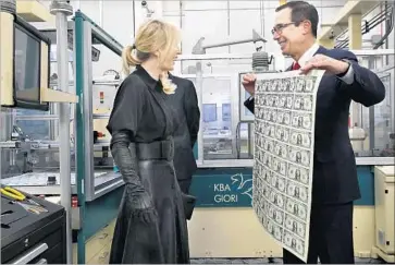  ?? Jacquelyn Martin Associated Press ?? TREASURY SECRETARY Steven Mnuchin shows off a sheet of $1 bills with his signature on them to his wife.