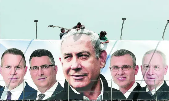  ?? REUTERS ?? Operarios cuelgan un cartel electoral durante la campaña de marzo donde aparece Netanyahu y candidatos de su partido, el Likud