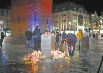  ??  ?? Una persona pone una vela en la plaza del mercado central en Halle, Alemania, después de que dos personas murieron en un tiroteo adentro de un restaurant­e turco.