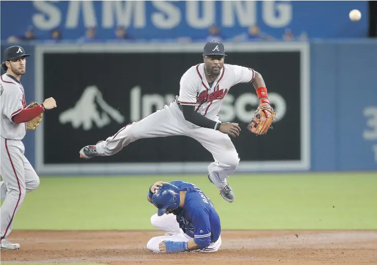  ?? — GETTY IMAGES ?? Brandon Phillips of the Atlanta Braves turns a double-play as Jose Bautista of the Blue Jays slides into second base at the Rogers Centre on Tuesday in Toronto.