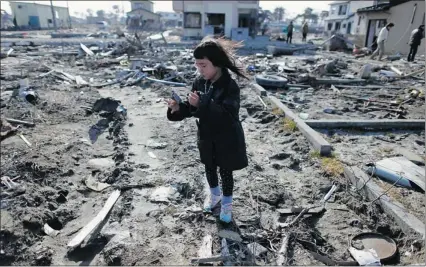  ?? TORU Hanai/reuters ?? Wakana Kumagai, 7, visits the spot Sunday where her house used to stand until it was washed away by the March 11, 2011
tsunami in Japan. Families gathered in towns and villages Sunday to mark the first anniversar­y of the quake disaster.