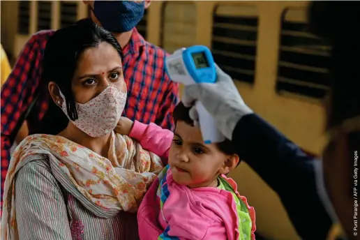  ?? ?? ARRIVALS: A passager with her child gets her temperatur­e checked after disembarki­ng a long-distance train in Mumbai