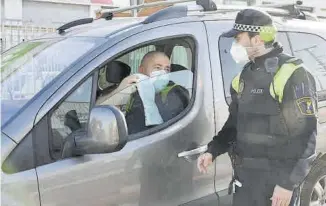  ??  ?? Un conductor muestra su justifican­te laboral a uno de los agentes de la Policía Local.