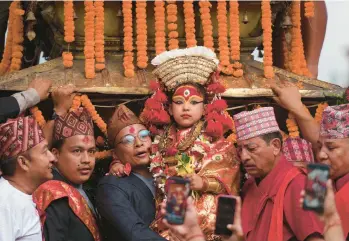  ?? NIRANJAN SHRESTHA/AP ?? Living goddess: Nepal’s revered living goddess Kumari is carried to a wooden chariot Friday during Indra Jatra, an eight-day religious festival in Kathmandu. The living goddess was pulled in her chariot around the main parts of the capital by devotees as tens of thousands of people lined up in the old city to get a glimpse of her and to be blessed.