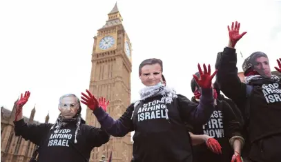  ?? (Hollie Adams/Reuters) ?? PRO-HAMAS protesters with red paint on their hands wear masks of UK Prime Minister Rishi Sunak, UK Foreign Secretary David Cameron, and Israeli Prime Minister Benjamin Netanyahu as they hold signs reading ‘Stop arming Israel,’ near Big Ben in London, earlier this year.