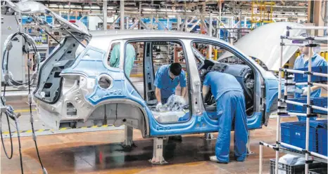  ?? FOTO: OLE SPATA/DPA ?? Mitarbeite­r montieren in einem VW-Werk bei Shanghai ein Fahrzeug: Das Coronaviru­s führt nicht nur bei dem Wolfsburge­r Autokonzer­n zu Problemen in Lieferkett­en und Logistik.