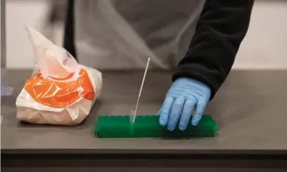  ?? Photograph: Oli Scarff/AFP/Getty Images ?? A member of staff in PPE collects a student’s swab as part of a lateral flow Covid test at the University of Hull in November.