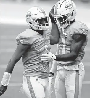  ?? JOHN MCCALL/SOUTH FLORIDA SUN SENTINEL ?? Dolphins quarterbac­k Tua Tagovailoa and wide receiver DeVante Parker embrace before their game against the Bengals in 2020.