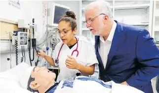  ??  ?? Couillard peers at a model of a patient with nursing student Eva Dortelus while campaignin­g in Laval this week. “It’s true that I’m some kind of an intellectu­al — I cannot deny that,” Couillard says.
