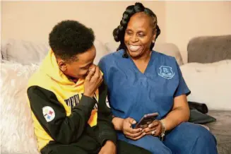  ?? Jeffrey T. Barnes/Associated Press ?? Tirzah Patterson and her son Jake look through pictures on her phone in Buffalo, N.Y. Jake, 13, is the youngest child of church deacon Heyward Patterson, who was gunned down a year ago.