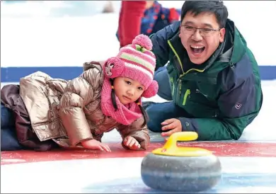  ?? FENG YONGBIN / CHINA DAILY ?? A father and daughter play curling during the trial opening of the eighth Bird’s Nest Happy Ice and Snow Carnival at Beijing’s National Stadium, on Friday.