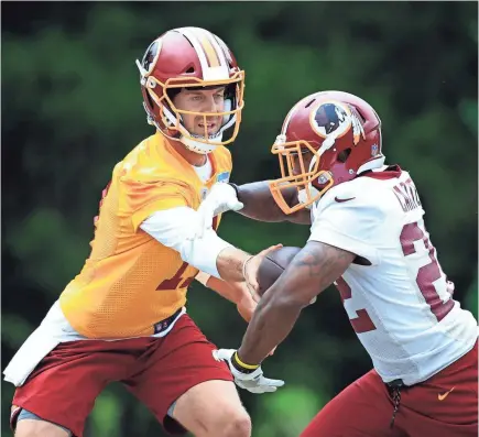  ??  ?? Washington quarterbac­k Alex Smith, left, hands off to running back Martez Carter on Wednesday.