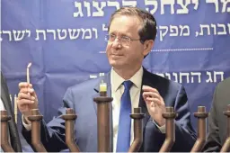  ?? OREN ZIV/AP ?? Israeli President Isaac Herzog lights candles Sunday during Hanukkah in the Israeli controlled part of the West Bank city of Hebron.