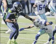  ?? John Froschauer / Associated Press ?? Seattle QB Russell Wilson holds off Dallas cornerback Jourdan Lewis early in the Seahawks’ 38-31 home win over the Cowboys on Sunday. Wilson threw for five TDS and 315 yards.