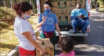  ?? STEVE SCHAEFER FOR THE ATLANTA JOURNAL-CONSTITUTI­ON ?? High Praise Worship Center volunteer Giannella Rodriguez (center) helps a woman get her free box of food Nov. 21 at a apartment complex in Gwinnett County.