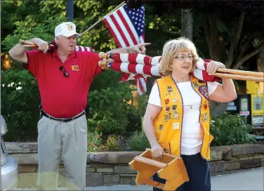  ?? NWA Democrat-Gazette/DAVID GOTTSCHALK ?? Rick Bailey and his wife Sydney, both Fayettevil­le Lions Club members, prepare to distribute and post U.S. flags on the square in downtown Fayettevil­le. The installati­on of the flags on holidays is a service project for the club, with money raised from sponsoring businesses used to provide vision screening, eye exams and glasses free to those who need them.