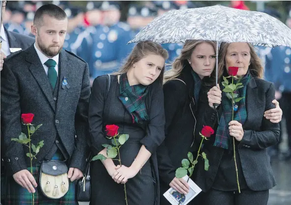  ?? — THE CANADIAN PRESS ?? Drew Davidson, left, and his sisters Fay and Dina stand with their mother Denise as they watch the casket of Abbotsford Police Const. John Davidson, killed in the line of duty on Nov. 6, being loaded into a hearse after a memorial in Abbotsford on...
