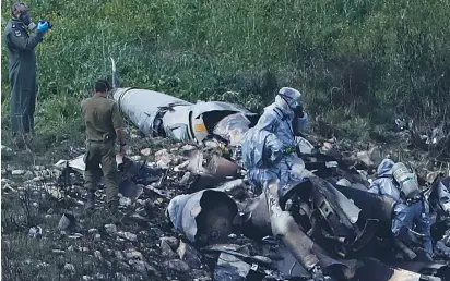  ?? (Ronen Zvulun/Reuters) ?? SECURITY PERSONNEL examine the remains of an Israel Air Force F-16 fighter plane near Kibbutz Harduf yesterday.