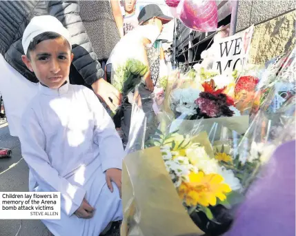  ??  ?? Children lay flowers in memory of the Arena bomb attack victims