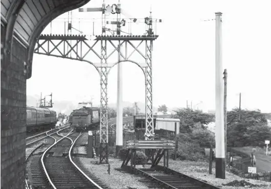  ?? R B Parr/SLS Collection ?? It’s all action at the east end of Haltwhistl­e station on 27 May 1953 as a Worsdell ‘G5’ class 0-4-4T arrives from Alston and three other locomotive­s make up the scene, seemingly up and down main line trains, and a light engine ‘K1’ occupying the distant up siding. Perhaps the branch train is timed to connect with the Carlisle bound working running in alongside. The alignment of the Alston branch is clear to see as it descends from the right of the view, and a somersault signal is off to allow entry into the regular branch platform, the southernmo­st. The dominant brick structure near left is the signal box, and at least two additional wooden posts offer stabilisin­g support for the nearby lattice post signals, which suggests an exposed location – there is open land unseen to the right and much of the near 180 degree approach of branch trains can be traced from a position on the down island. The incoming branch is single-track, the additional line at the lower level being a lengthy siding, complete with a kick back addition that is occupied by a hopper wagon.