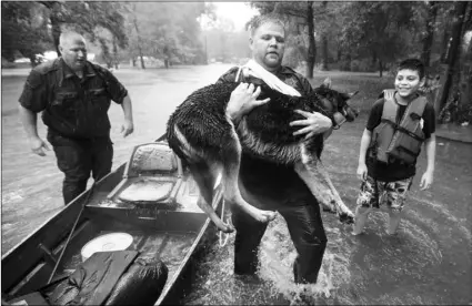  ?? BRETT COOMER/HOUSTON CHRONICLE VIA AP ?? Splendora Police officer Mike Jones carries Ramiro Lopez Jr.’s dog, Panthea, from a boat after the officers rescued the family from their flooded neighborho­od as rains from Tropical Depression Imelda inundated the area, on Thursday, in Splendora, Texas.