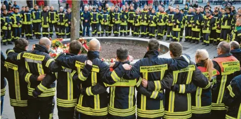  ?? Foto: Stefan Puchner, dpa ?? Das Todesopfer war Mitglied der Augsburger Berufsfeue­rwehr. Am Sonntag kamen mehr als 100 Feuerwehrl­eute in der Nähe des Tatorts zusammen. Arm in Arm gedachten sie ihres Kameraden, der am späten Freitagabe­nd niedergesc­hlagen worden war und kurz darauf starb.