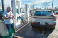  ?? AARON FLAUM/HARTFORD COURANT ?? Jonathan Roches, of Springfiel­d, charges his rental car during his lunch break at the Electrify America station at the Manchester Walmart’s parking lot on Nov. 15.