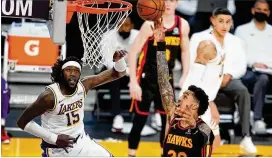  ?? PHOTOS BY MARCIO JOSE SANCHEZ/AP ?? The Hawks’ John Collins scores past the Lakers’ Montrezl Harrell on Saturday in Los Angeles. Collins had 27 points and 16 rebounds in the 99-94 win.