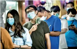  ?? ?? A man using a fan to cool off as residents queue to undergo nucleic acid tests for Covid-19 in Guangzhou, in China's southern Guangdong province. (AFP)