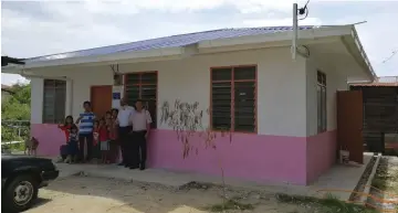  ??  ?? Low (left) and his family give the thumbs-up outside their new house. Karambir is at second right.